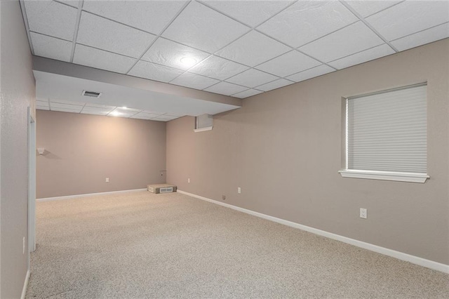 finished below grade area with baseboards, visible vents, a drop ceiling, and carpet