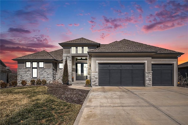 prairie-style home with a front yard, driveway, stucco siding, stone siding, and a garage