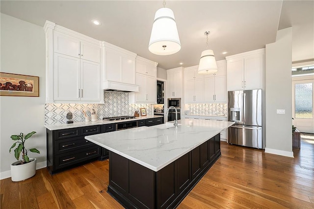 kitchen with pendant lighting, dark wood-style floors, dark cabinetry, appliances with stainless steel finishes, and white cabinets