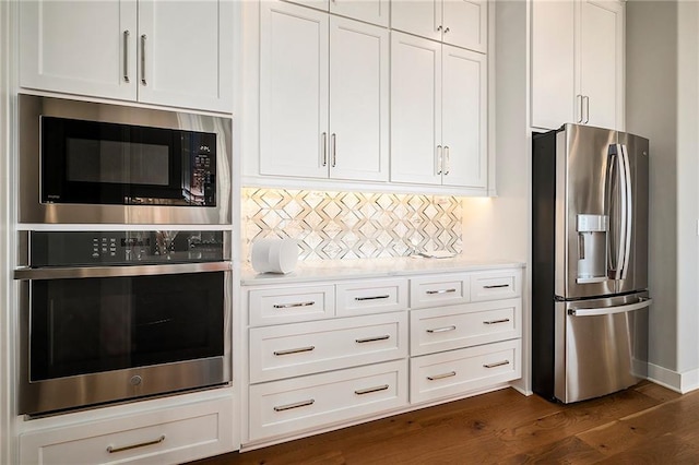 kitchen with tasteful backsplash, stainless steel fridge, light countertops, built in microwave, and dark wood-style flooring