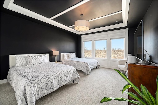 carpeted bedroom with a raised ceiling and an inviting chandelier