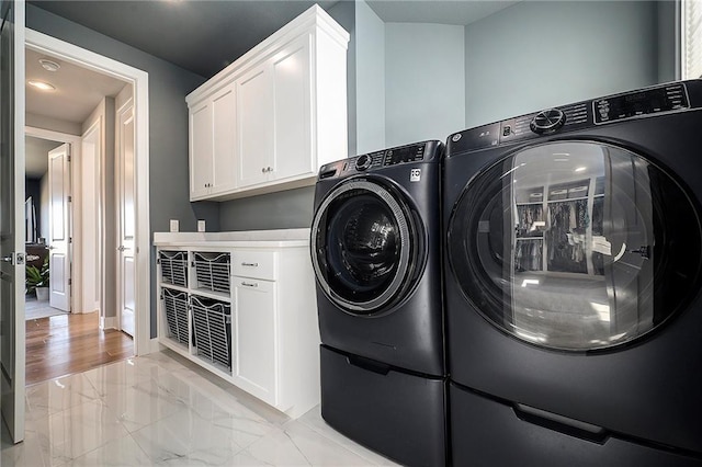 laundry room featuring washer and dryer, baseboards, cabinet space, and marble finish floor