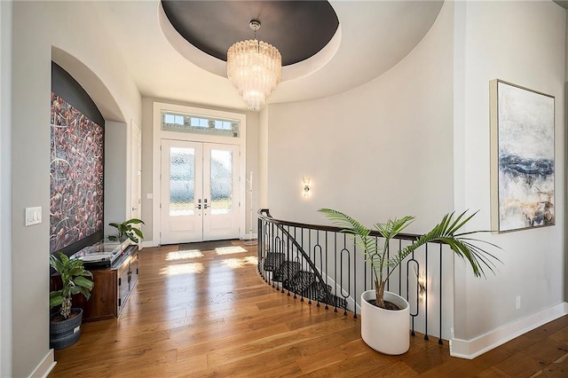 foyer entrance with french doors, baseboards, an inviting chandelier, and hardwood / wood-style floors