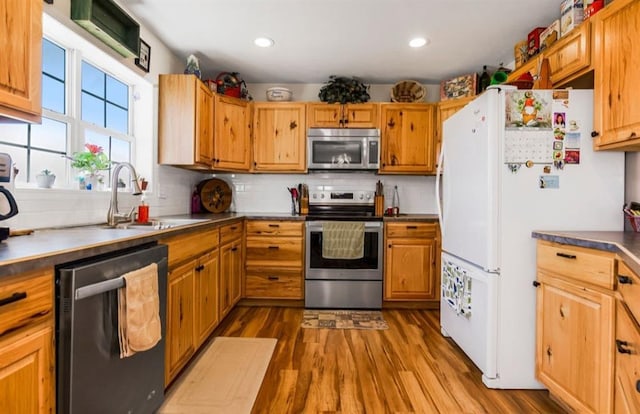 kitchen featuring a sink, backsplash, wood finished floors, recessed lighting, and stainless steel appliances