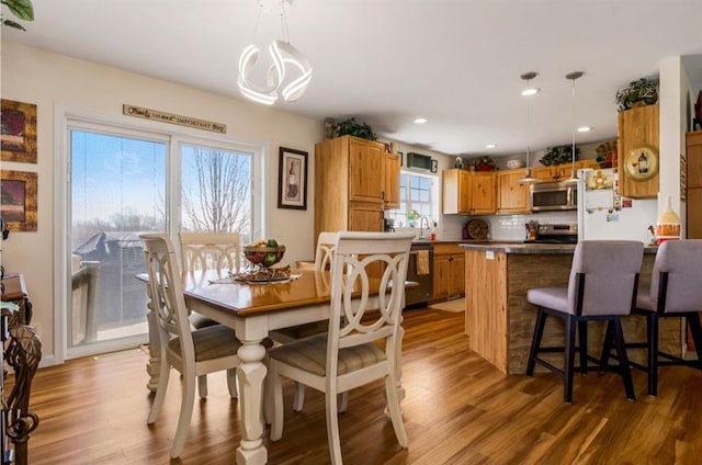 dining room with a notable chandelier, recessed lighting, and wood finished floors