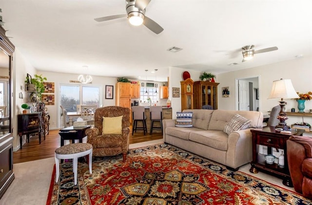 living room with light wood-style floors, a ceiling fan, and visible vents