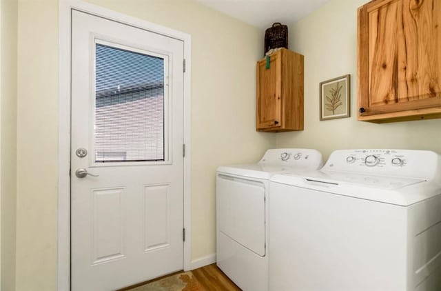 laundry room featuring cabinet space, wood finished floors, separate washer and dryer, and baseboards