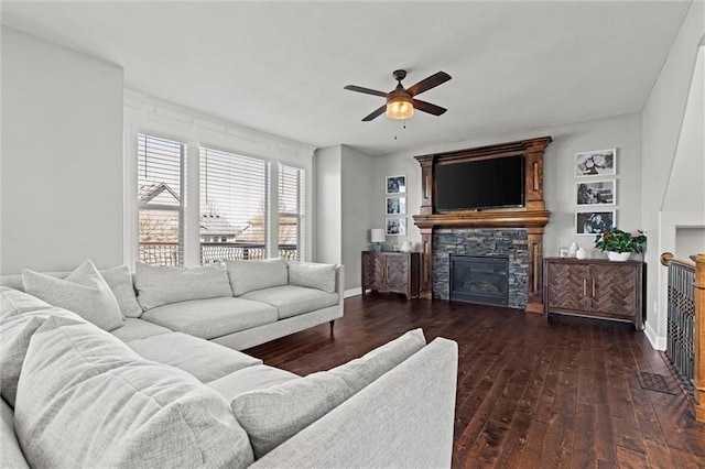 living room with dark wood-style floors, ceiling fan, a fireplace, and baseboards