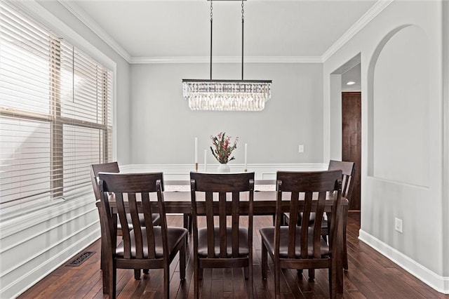 dining area with hardwood / wood-style flooring, arched walkways, and crown molding