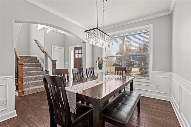 dining room featuring crown molding, stairway, dark wood finished floors, and arched walkways