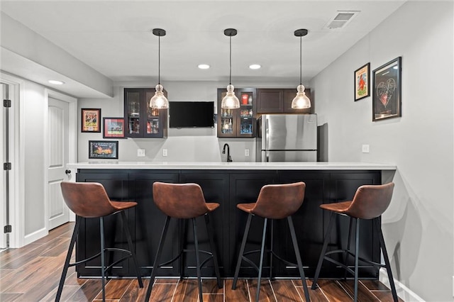 bar featuring visible vents, hanging light fixtures, dark wood-type flooring, freestanding refrigerator, and wet bar