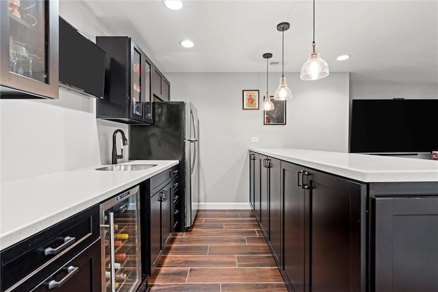 kitchen featuring wine cooler, light countertops, a sink, and wood tiled floor