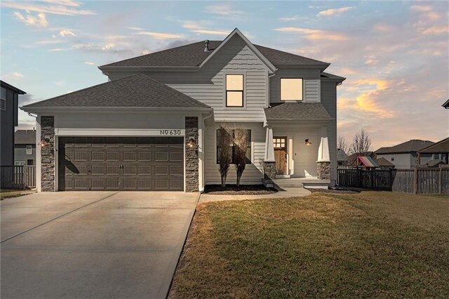 630 N Laurel St, Gardner, KS 66030 - traditional home featuring fence, a front lawn, stone siding, a garage, and concrete driveway