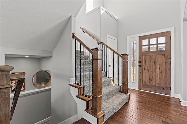 entrance foyer featuring a textured ceiling, vaulted ceiling, stairway, baseboards, and hardwood / wood-style floors