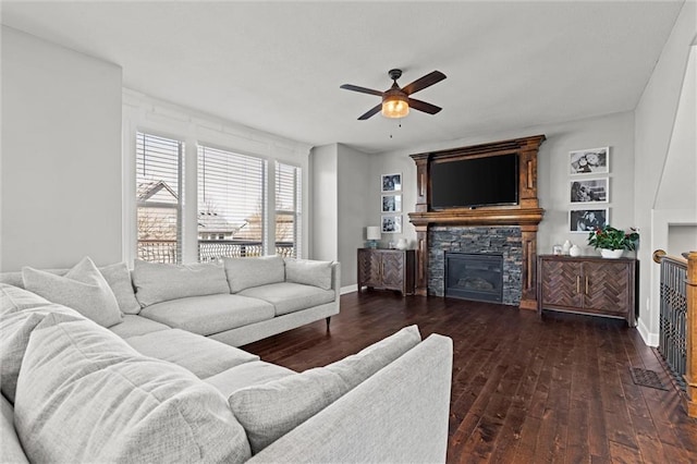 living room with baseboards, ceiling fan, a fireplace, and dark wood-type flooring