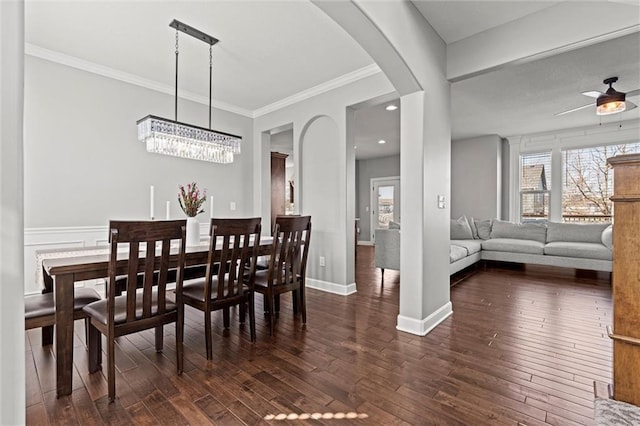 dining space with crown molding, arched walkways, dark wood-style flooring, and ceiling fan with notable chandelier
