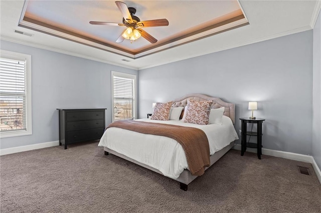 carpeted bedroom with crown molding, visible vents, baseboards, a raised ceiling, and a ceiling fan