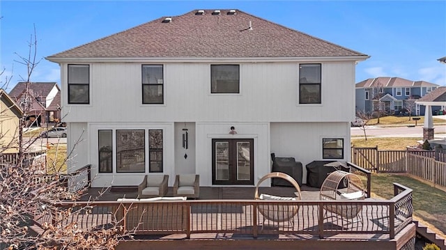 rear view of house with a shingled roof, a fenced backyard, french doors, and a wooden deck