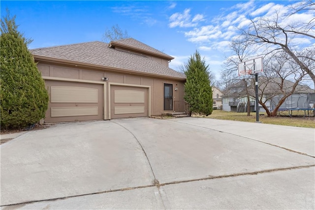 132 The Woodlands Dr, Gladstone, MO 64119 - view of property exterior featuring a shingled roof, stucco siding, an attached garage, driveway, and a trampoline