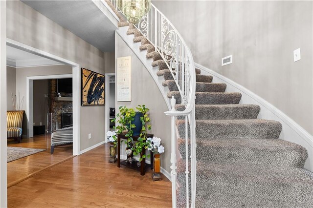 132 The Woodlands Dr, Gladstone, MO 64119 - stairs featuring baseboards, ornamental molding, wood finished floors, and visible vents