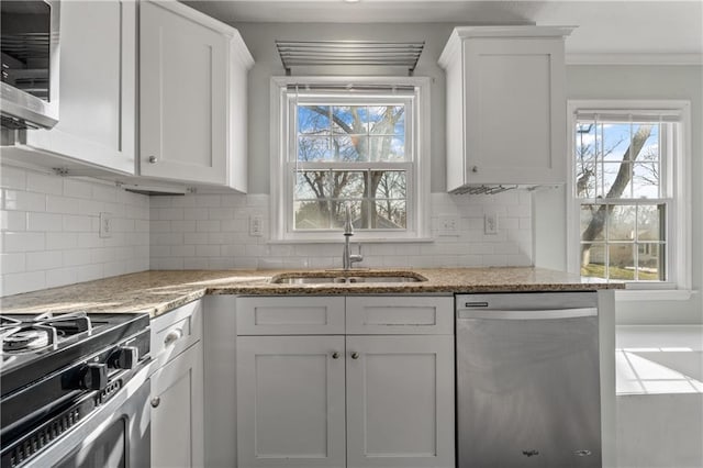 kitchen featuring a sink, white cabinetry, appliances with stainless steel finishes, decorative backsplash, and light stone countertops