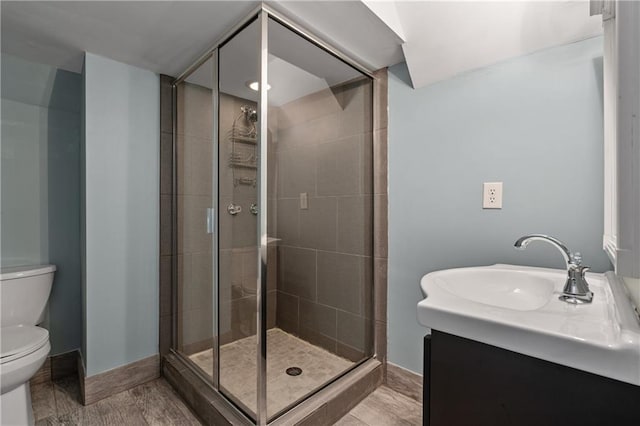 bathroom with a shower stall, toilet, vanity, and baseboards