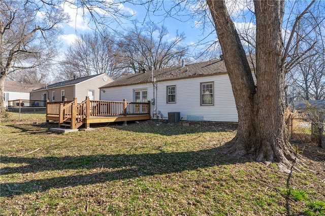 rear view of property featuring a deck, cooling unit, fence, and a yard