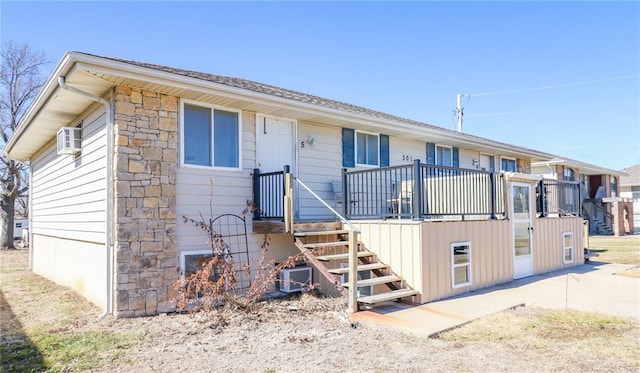 view of front of property featuring stone siding, stairway, and central AC unit