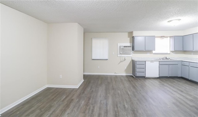 kitchen with dark wood-style floors, gray cabinets, light countertops, and white dishwasher