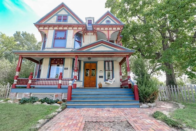 victorian-style house with covered porch and fence