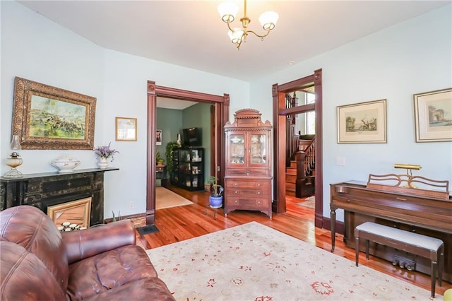 living room with a notable chandelier, a premium fireplace, wood finished floors, baseboards, and stairs