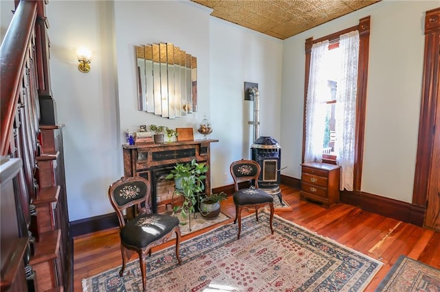 living area with hardwood / wood-style flooring, a fireplace, an ornate ceiling, and baseboards