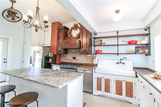 kitchen featuring a sink, stainless steel appliances, a kitchen bar, and open shelves