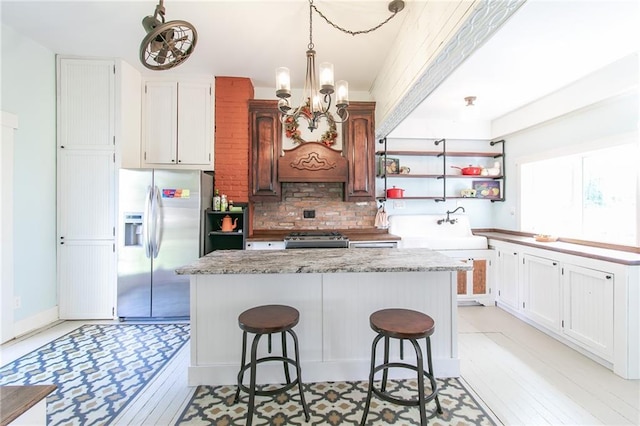 kitchen with a kitchen island, stainless steel appliances, a kitchen bar, a chandelier, and backsplash