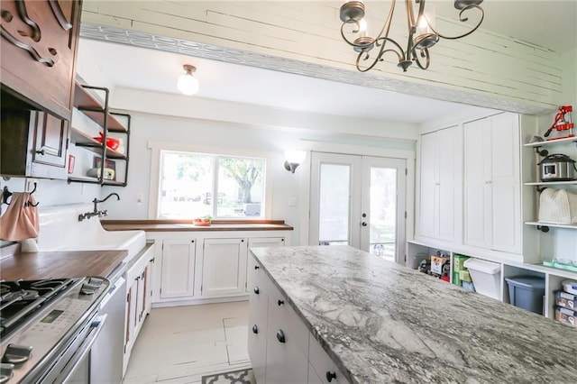 kitchen featuring stainless steel gas stove, dark stone counters, open shelves, and french doors