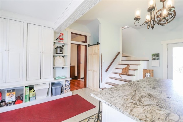 kitchen featuring a barn door, a kitchen breakfast bar, an inviting chandelier, white cabinetry, and open shelves