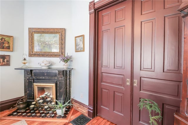 entrance foyer featuring a premium fireplace, light wood-style flooring, and baseboards