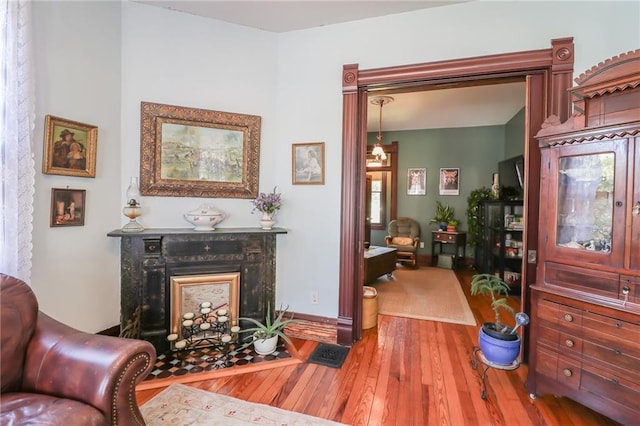 living area with baseboards, visible vents, hardwood / wood-style floors, and a high end fireplace