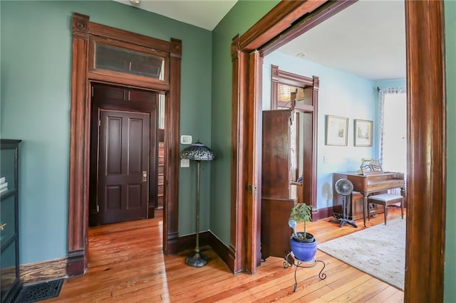 hall featuring visible vents, hardwood / wood-style flooring, and baseboards