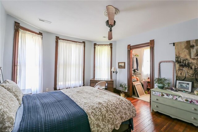 bedroom with dark wood-style floors, a walk in closet, and visible vents