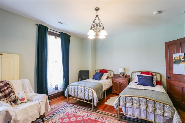 bedroom with a chandelier, visible vents, and wood finished floors