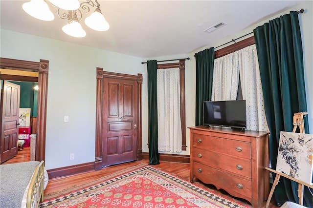 bedroom featuring light wood-type flooring, baseboards, visible vents, and a notable chandelier