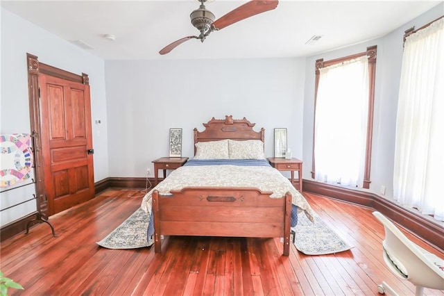 bedroom with a ceiling fan, multiple windows, hardwood / wood-style flooring, and baseboards