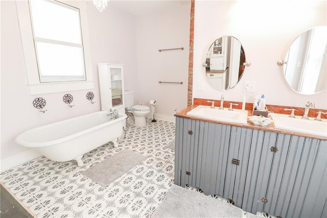 full bathroom featuring double vanity, a freestanding tub, a sink, and toilet