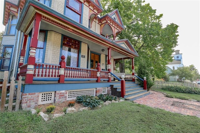 victorian house featuring a porch and fence