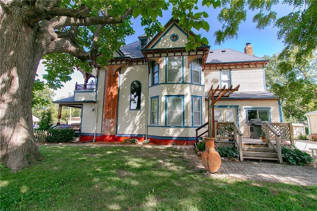 view of front of property featuring a front yard, a chimney, and a balcony