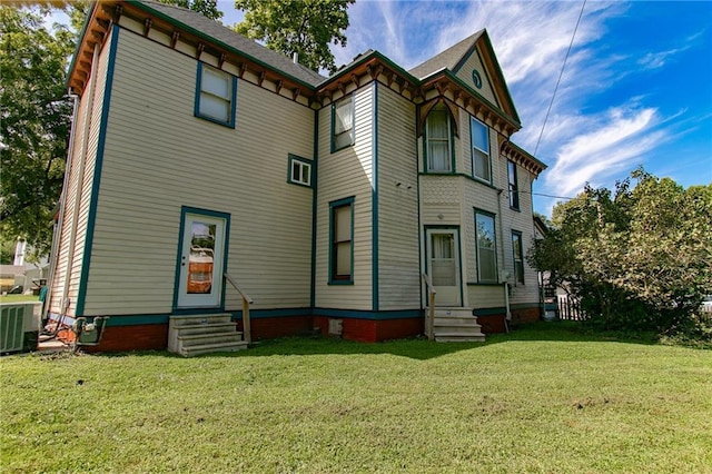 back of house with entry steps, a yard, and central AC unit