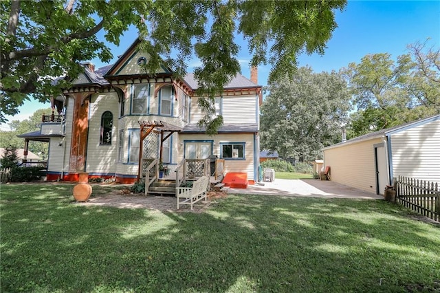 back of house featuring a yard, a chimney, a patio area, and fence