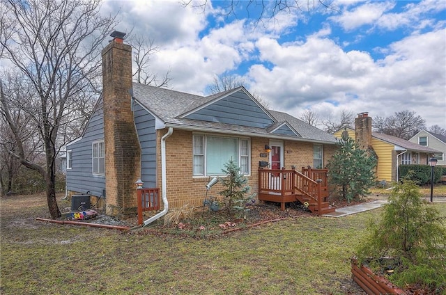 bungalow featuring roof with shingles, a front yard, a chimney, and brick siding