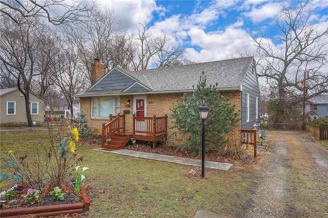 view of front of home featuring brick siding, fence, a chimney, and a front lawn